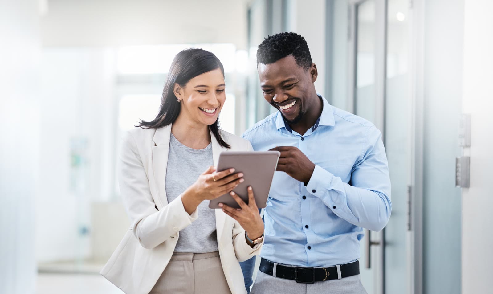 Two colleagues smiling at a tablet