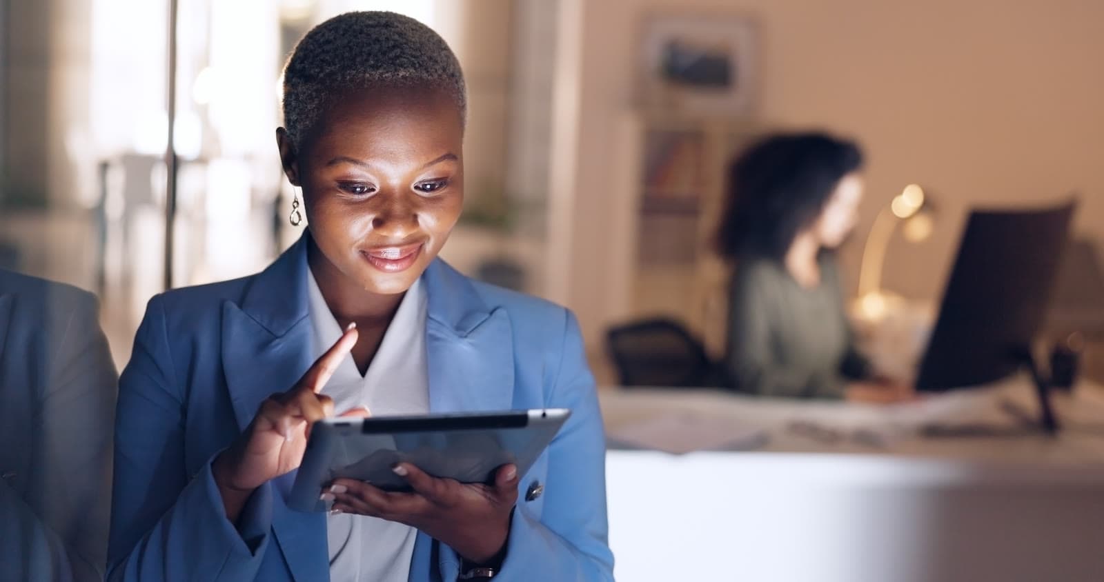Woman smiling at a tablet in an office